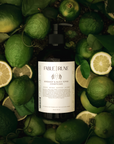 Bottle of Fable & Rune soap surrounded by bergamot citrus and leaves on a dark background