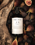 Bottle of body lotion surrounded by figs and wood