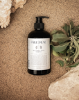 Bottle of Fable & Rune shampoo on a textured surface with rocks and leaves