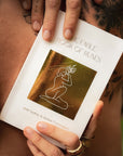 Person holding a book titled 'The Fable Book of Runes' with visible tattoos on hands.