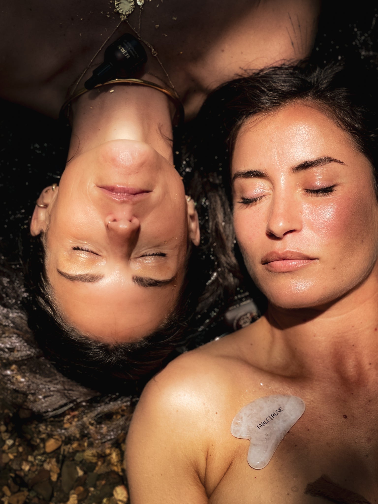 Two people lying on a rock with one person wearing a heart-shaped tattoo on their chest.