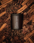 Black candle in a circle of cinnamon sticks, star anise, and other spices