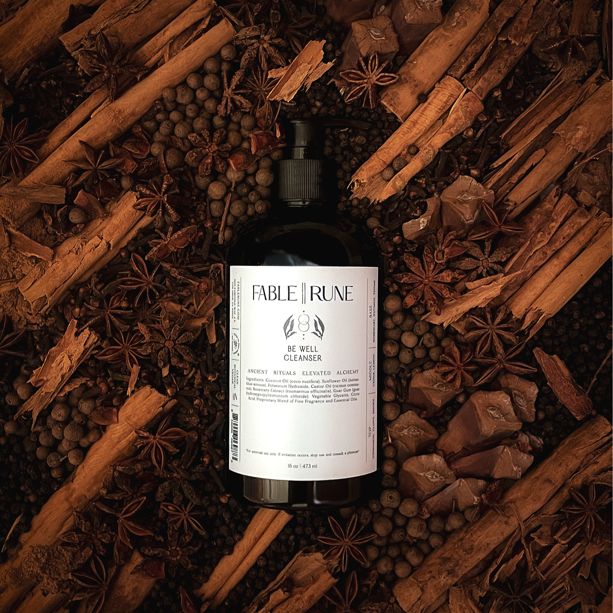 Bottle of Fable & Rune product surrounded by cinnamon sticks and star anise on a dark background