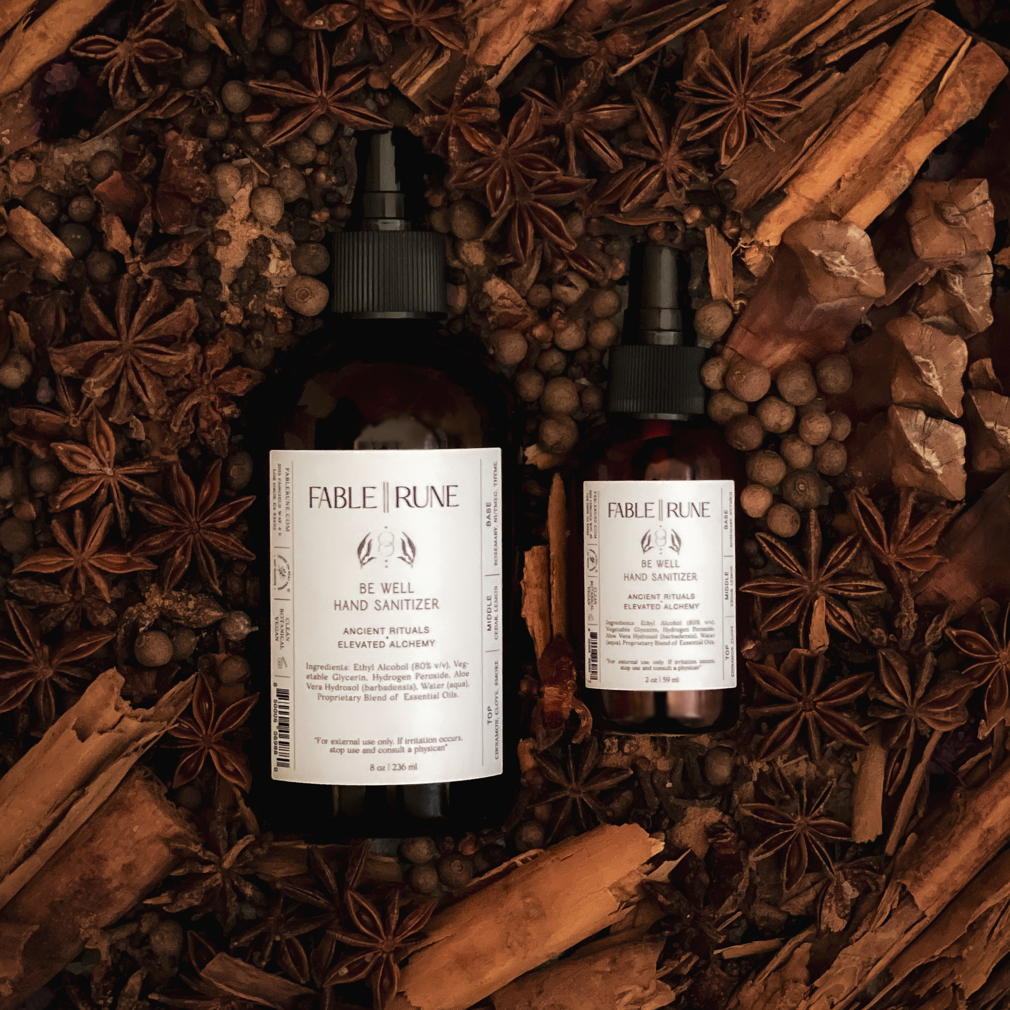 Two bottles of Fable & Rune hand sanitizer surrounded by cinnamon sticks and star anise.