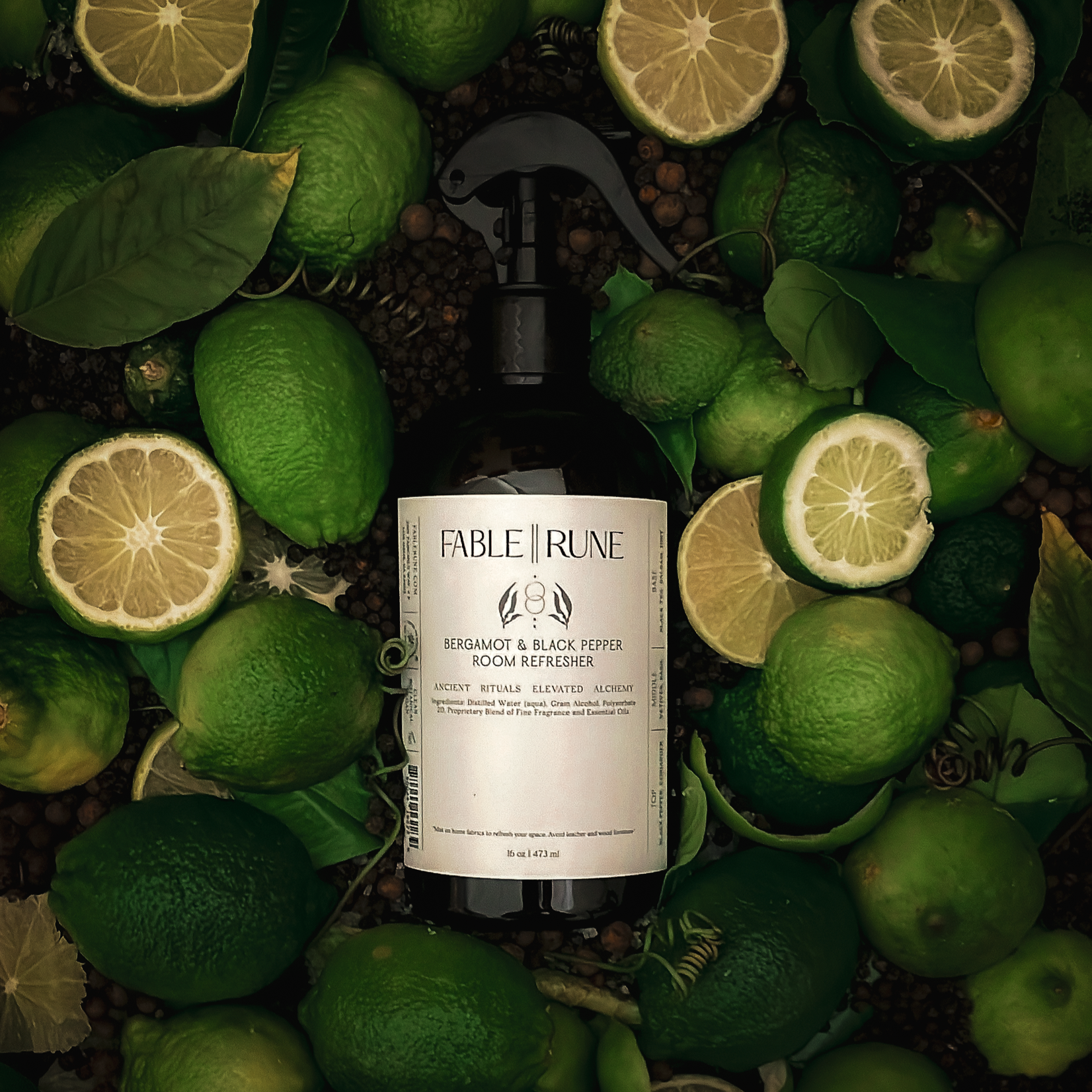 Bottle of room refresher surrounded by bergamot citrus and green leaves