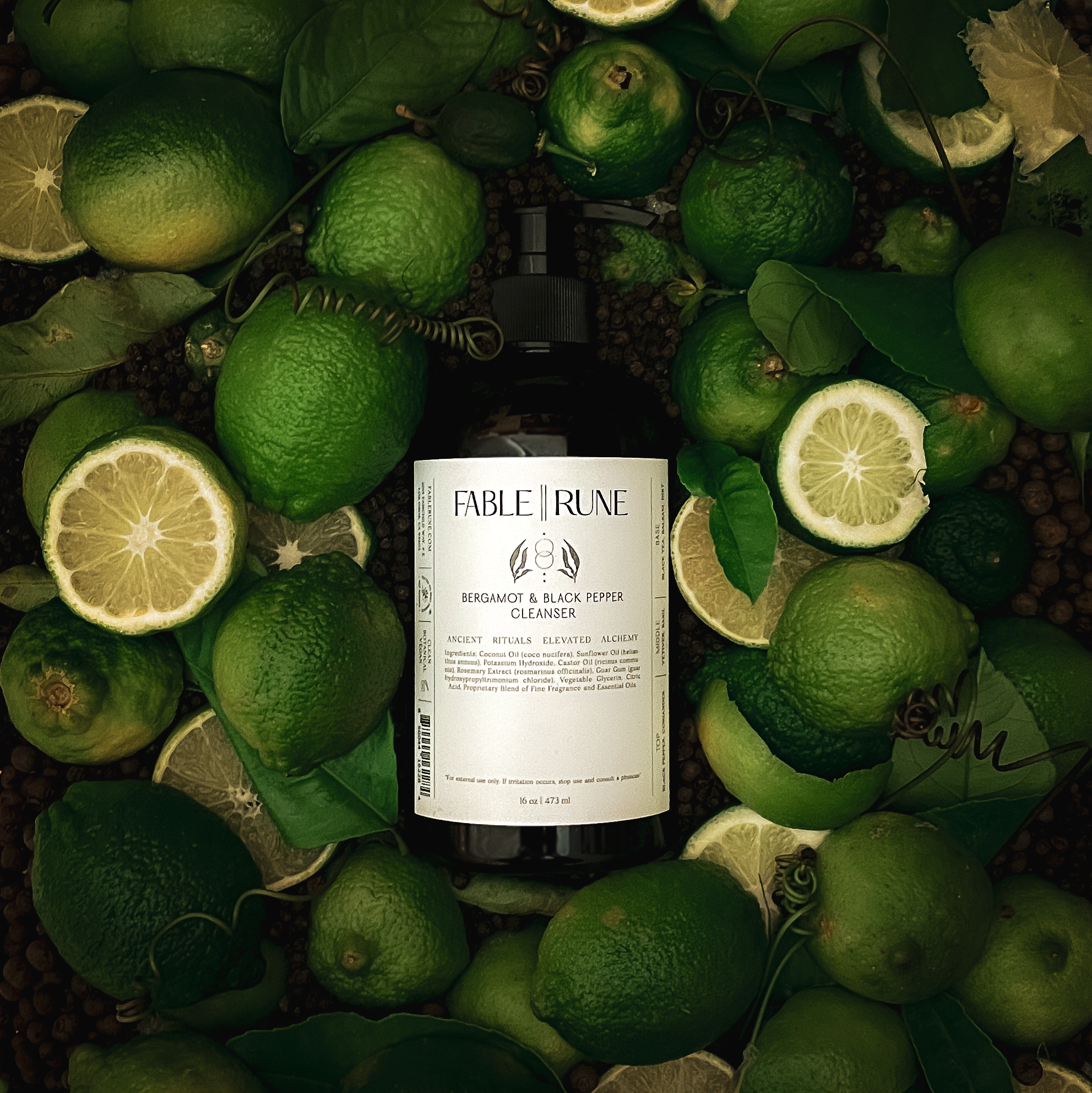 Bottle of Fable & Ruin cleanser surrounded by bergamot citrus and pepper