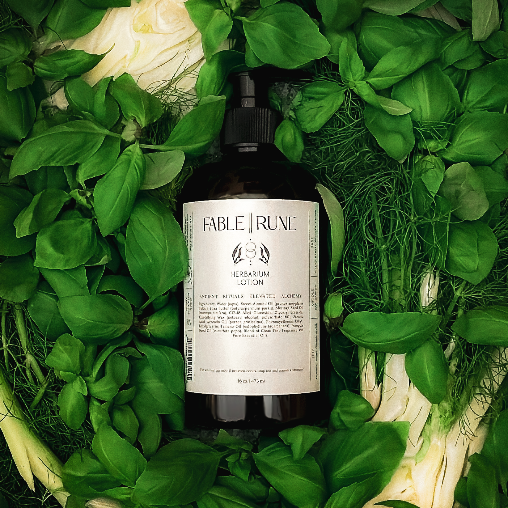 Bottle of Fable Truue lotion surrounded by green basil leaves and fennel bulbs