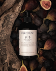 Bottle of body cleanser product surrounded by figs and natural wood elements