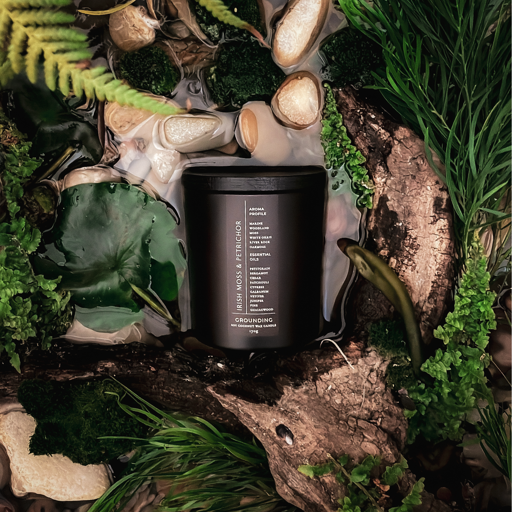 Black candle  on a natural setting with plants and stones