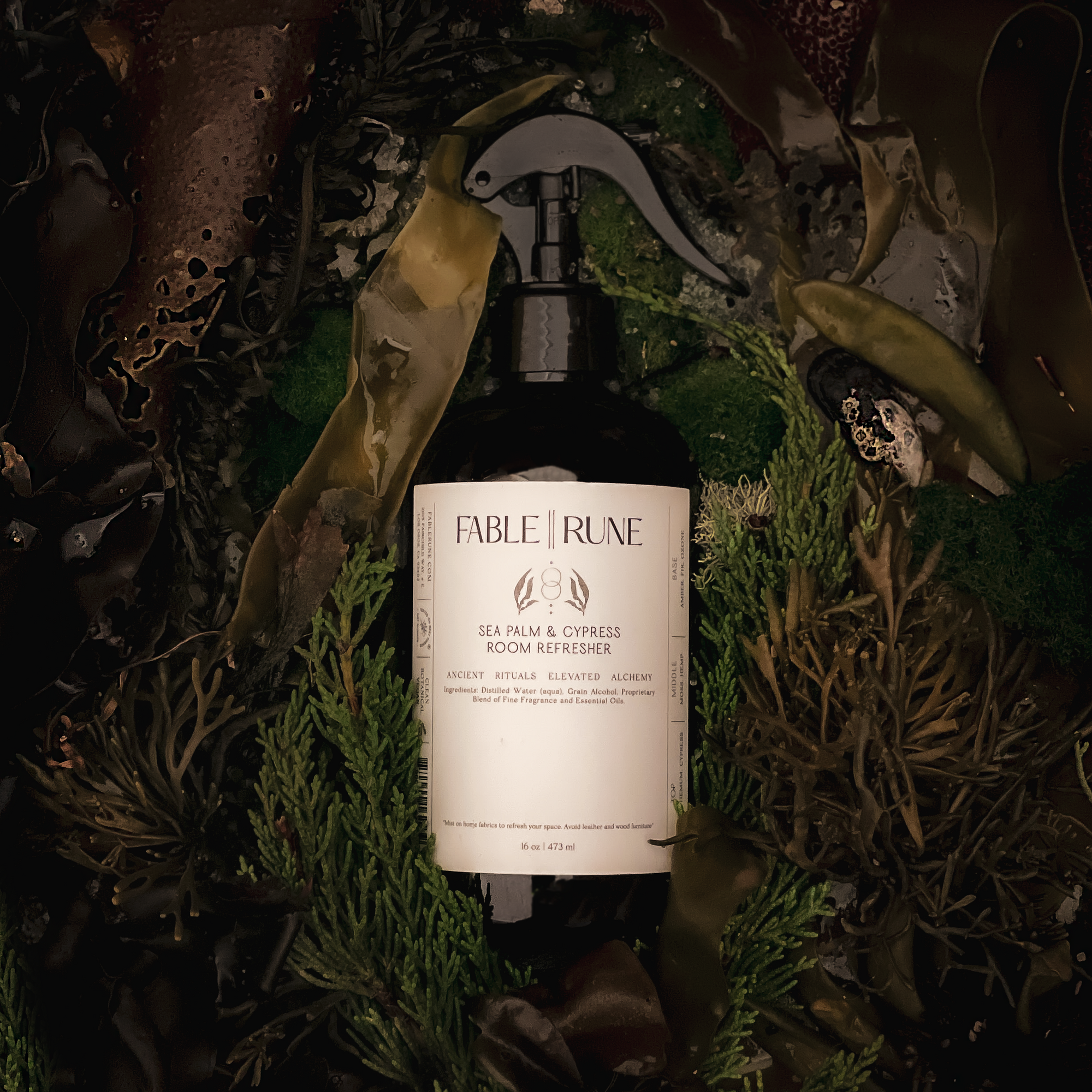 Bottle of sea palm cypress room refresher spray surrounded by greenery