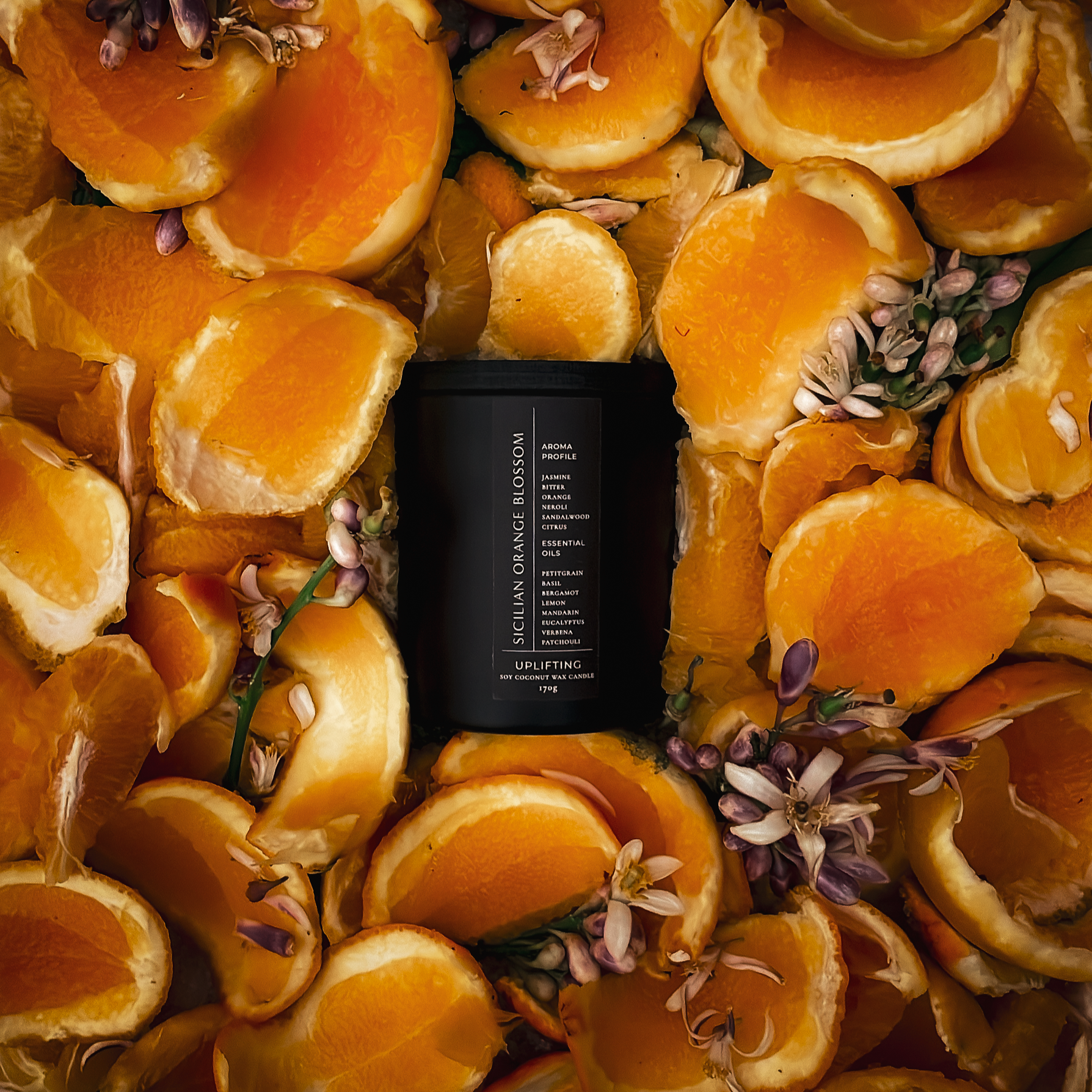 Black candle surrounded by sliced oranges and flowers