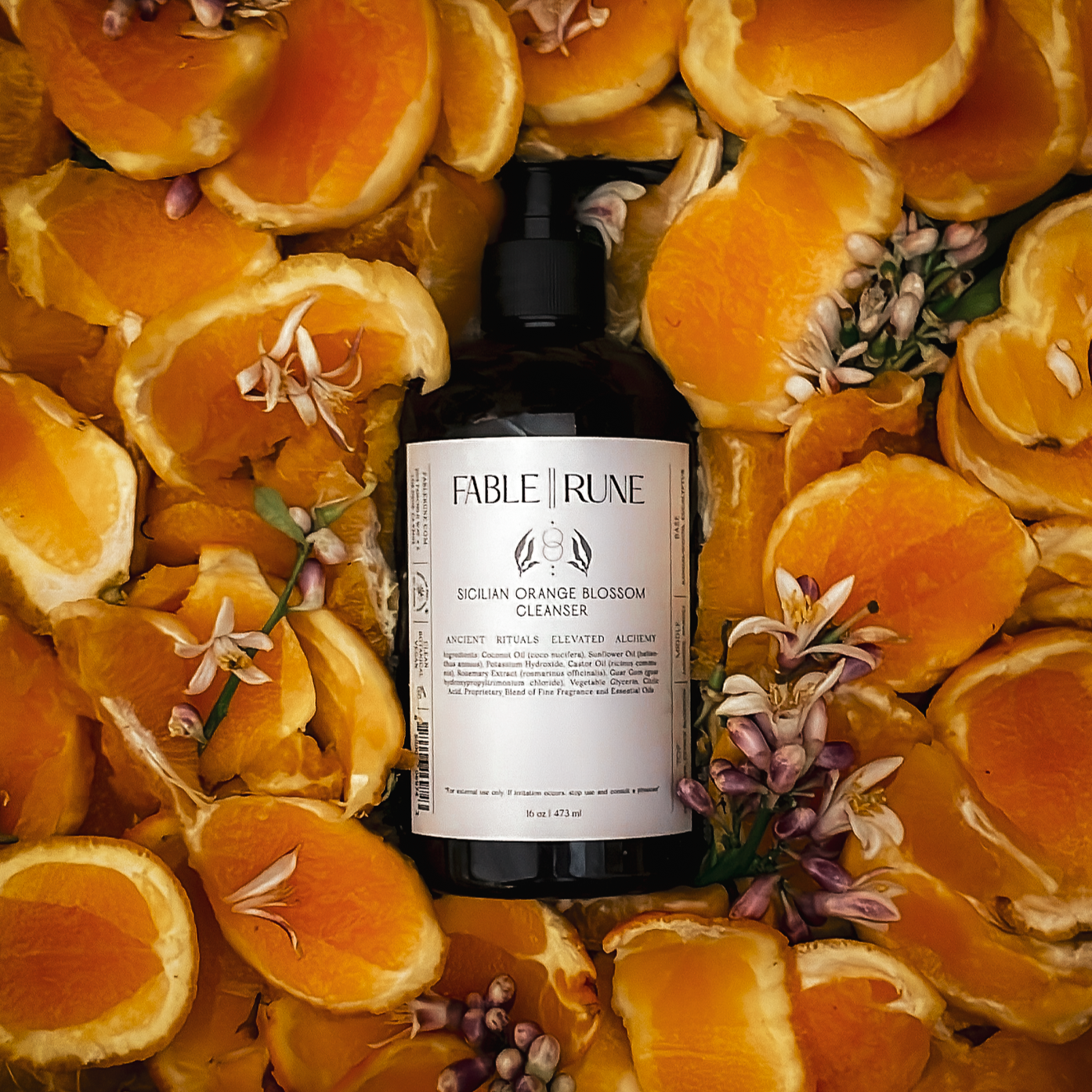 sicilian orange blossom body cleanser surrounded by sliced oranges and flowers