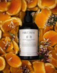 sicilian orange blossom body cleanser surrounded by sliced oranges and flowers