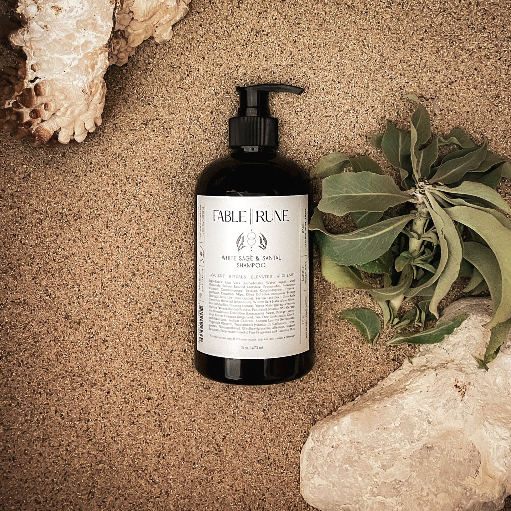 Bottle of Fable & Rune shampoo on a textured surface with rocks and leaves
