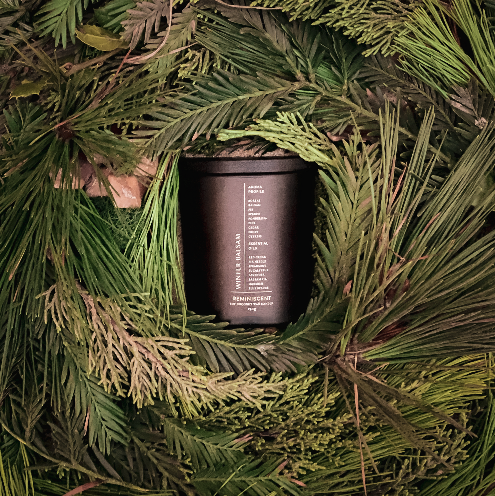 Candle in a wreath of greenery with a label on it