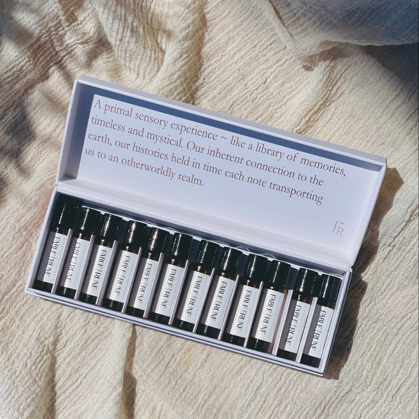 A set of travel size perfume rollers displayed in a box, with each roller labeled with different fragrance names like Bergamot & Black Pepper, Be Well, Herbarium, and others.