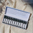 A set of travel size perfume rollers displayed in a box, with each roller labeled with different fragrance names like Bergamot & Black Pepper, Be Well, Herbarium, and others.